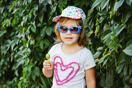 sweet toddler girl with lollipop and sun glassesの写真素材