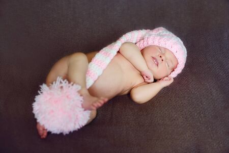 Cute little newborn baby is wearing pink pompom hatの写真素材