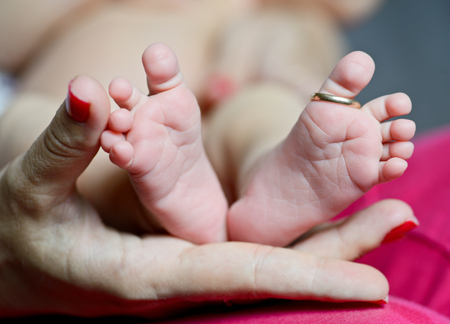 newborn's foot in the mother hand with wedding ring on fingerの写真素材