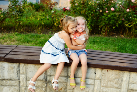 two happy little girls are hugging outdoorsの写真素材