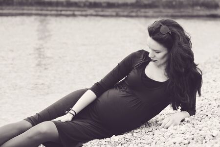 pregnant woman sitting on the beach in springの写真素材