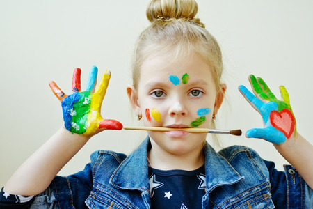 beautiful little girl with her hands in the paint