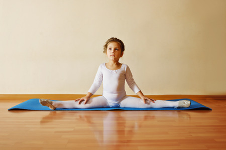 sweet toddler girl sitting in cross splitの写真素材