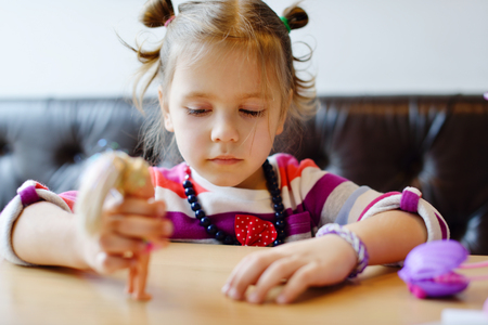 little girl playing dolls under the tableの写真素材