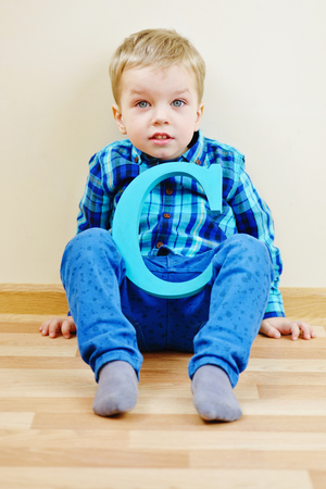 toddler blonde boy with a wooden letter Cの写真素材