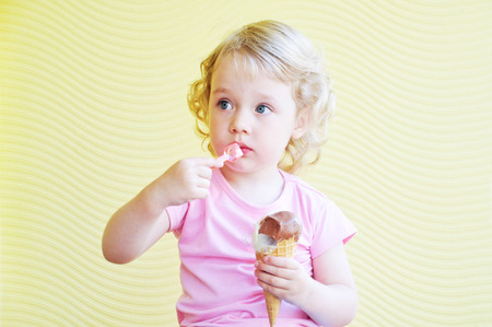 little girl  eating big ice cream cone in cafeの写真素材