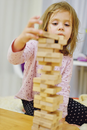 little girl with wooden blocks playing at homeの写真素材
