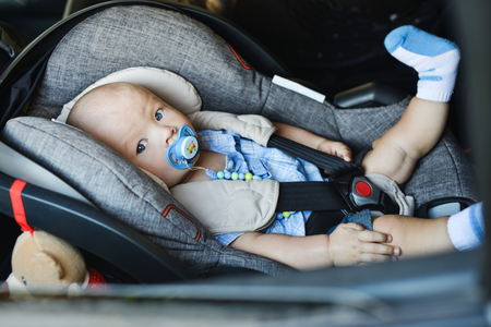 baby boy sitting in car seat anf looking in window の写真素材