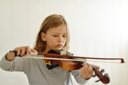 little girl playing the violin at homeの写真素材