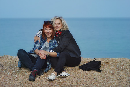 Two smiling female friends hugging each other on the beach