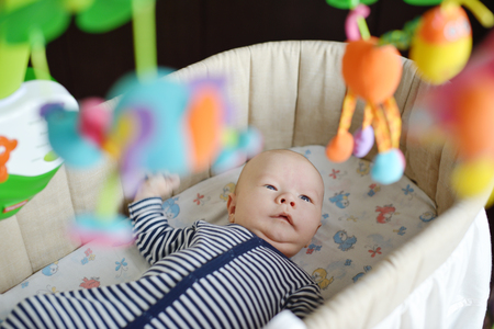 baby in crib looking at the colorful baby mobileの写真素材