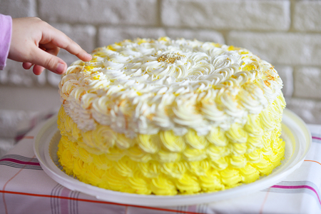 child's finger is touching the birthday  cake in soft selective focus