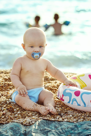 baby on the beach sitting on the pebbleの写真素材