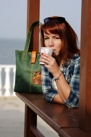 redhead woman with coffee in outdoors cafeの写真素材