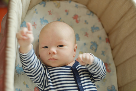 funny newborn in the crib with hands upの写真素材