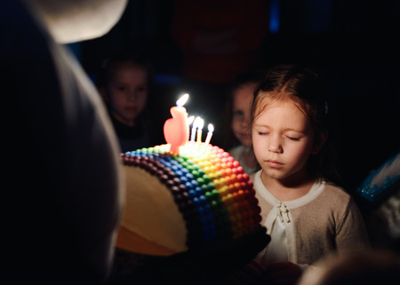 girl with birthday cake with caldles wishing in darkness
