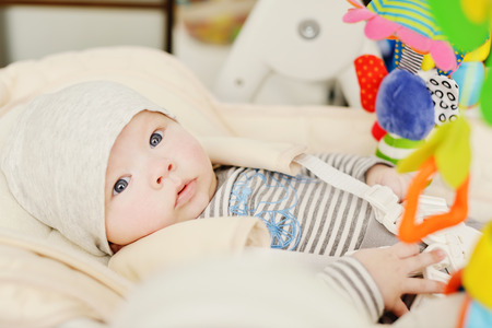 baby laying in bouncer chair and playing toy