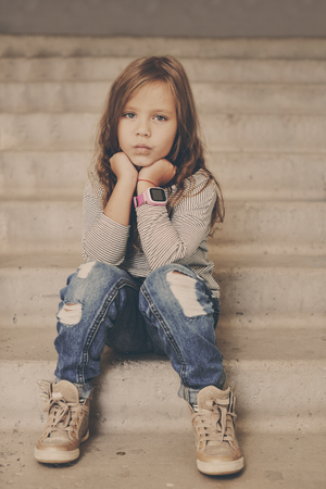 fashion little girl sitting on the stairsの写真素材