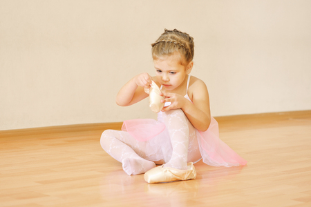 little beautiful ballerina looking on pointe  shoes on floorの写真素材