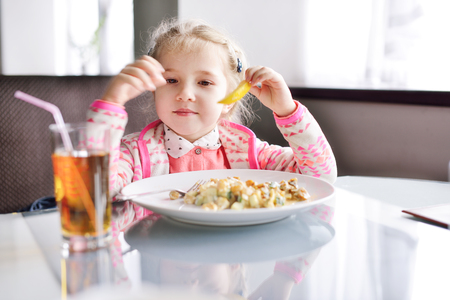 little girl sitting at the table in cafeの写真素材