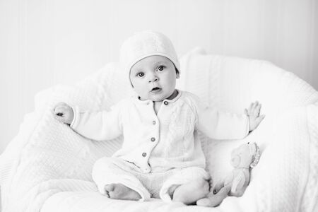 sweet baby wearing knitted suit is sitting on the arm-chairの写真素材