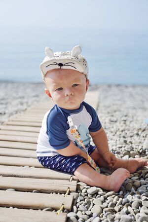 Little baby boy wearing  UV and sun protection  suit  on the beach.の写真素材