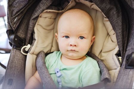 baby boy sitting  in the grey strollerの写真素材
