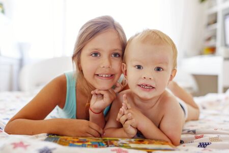 brother and sister  reading a book  on a  bed withの写真素材
