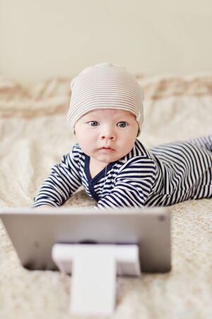 baby with tablet pc on the bedの写真素材