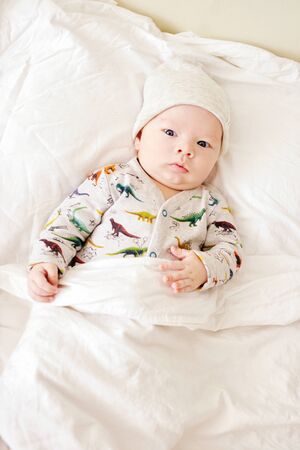 baby boy on the parents bed on the pillowの写真素材