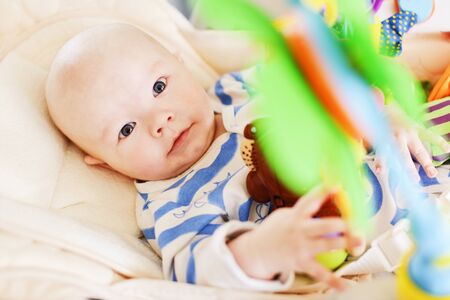 baby laying in bouncer chair and playing toyの写真素材