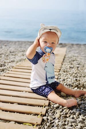 funny little baby boy on the beach wearing UV and sun   protective swim suitの写真素材