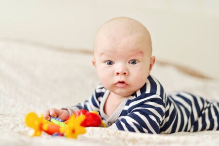 funny baby lying on the bed with toysの写真素材