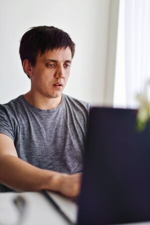 casual caucasian man working on laptop at the tableの写真素材