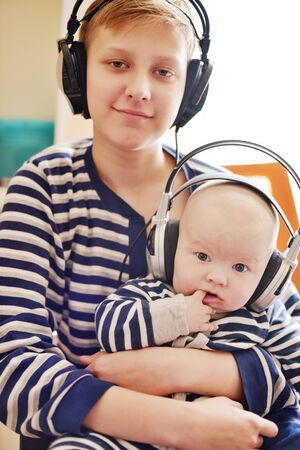 teen boy and his baby brother wearing headphones at homeの写真素材