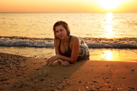 teen girl in the sea in sunset timeの写真素材