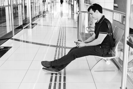 young caucasian man using a smartphone during waiting of trainの写真素材