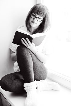 reading student girl with book near the windowの写真素材