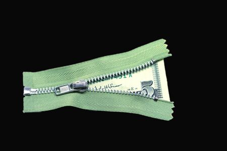 This is a nice shot of a green zipper on black that has been unzipped partway in order to reveal a crisp US five dollar bill.の写真素材