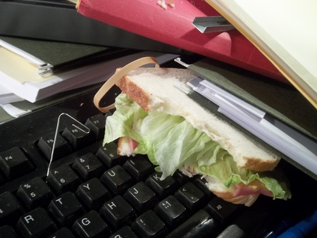 Sandwich of an office worker buried under files on a filthy keyboard.の写真素材
