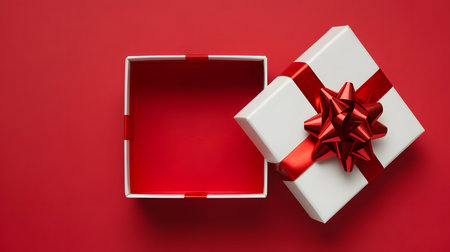 White gift box with red bow on red background. Top view.の素材