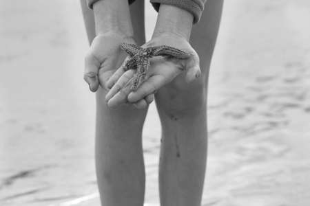 Hands holding a 4 legged starfish