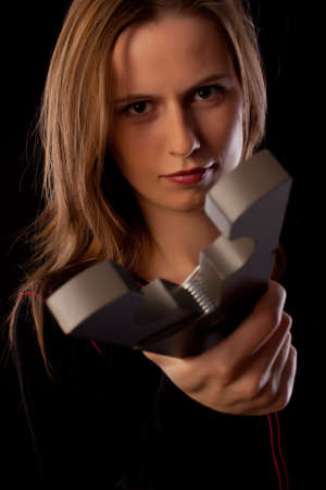 Serious young woman threatens you by huge pin on black backgroundの写真素材