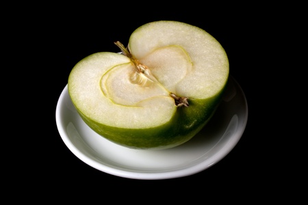 Half of a green apple on a plateの写真素材
