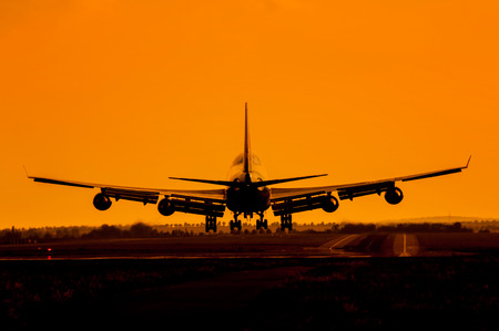 Huge plane with four engines landing in sunsetの写真素材