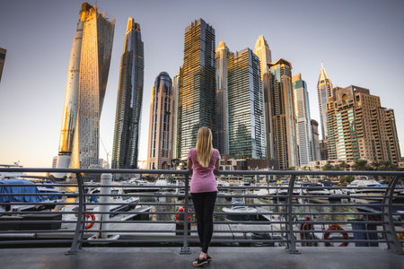 Woman looking up in awe at the towering skyscrapers of Dubai Marina.