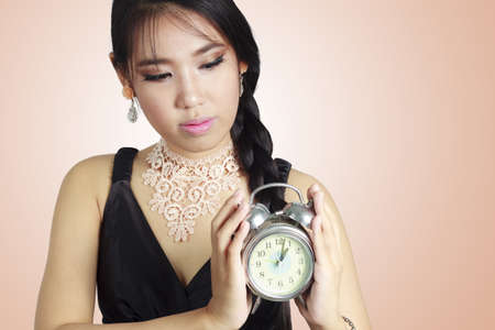 Asian woman holding a clock 