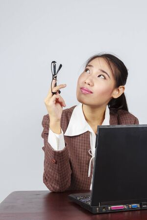 Portrait of elegant Asian business woman contemplating while holding glasses at officeの写真素材