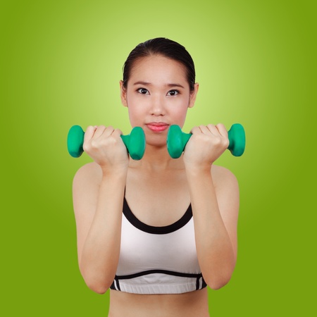 portrait of Asian woman doing fitness with weights over a green backgroundの写真素材
