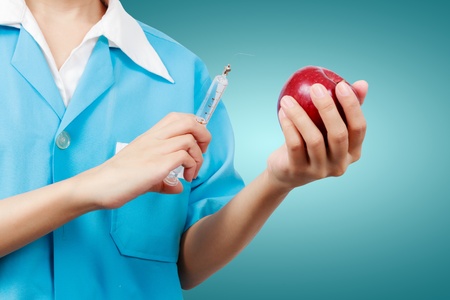 Female dentist holding an apple and syringes for teeth dental care.の写真素材